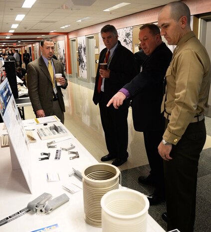 Craig Hughes from Johns Hopkins Applied Physics Lab (APL) points to a piece of U.S. Marine Corps Expeditionary hardware and highlights the additive manufacturing process used to Dr. John Burrow (center), deputy assistant Secretary of the Navy for research, development, test and evaluation, during the 3-D Print-a-thon hosted by the Navy at the Pentagon on March 15, 2017. Fellow project participants Steve Laderman from Carderock’s Propulsor Manufacturing Office (Code 6102) and Marine Capt. Matthew Friedell listen. (U.S. Navy photo by Kelley Stirling/Released)