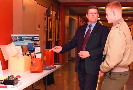 Mark Blocksom, left, the deputy department head of fleet and logistics support, SPAWAR Systems Center Pacific, discusses innovative 3D printing solutions to everyday military operations with Cpl. Christopher Bigham, from Waldorf, Md., during the Department of the Navy's 2017 3D Print-a-Thon expo at the Pentagon. Twenty DoN organizations - including scientists and engineers from the Naval Research and Development Establishment, maintenance operations, and Marines and Sailors from multiple commands - presented items produced through the use of Additive Manufacturing technology. Naval Surface Warfare Center Dahlgren Division coordinated the event, sponsored by the deputy assistant secretary of the Navy for research, development, test and evaluation. (U.S. Navy photo by Mass Communication Specialist 2nd Class Alex L. Smedegard/Released)