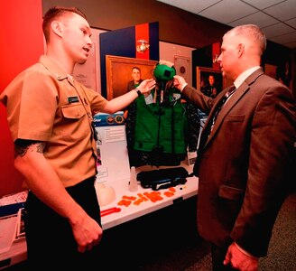 Aviation Electronics Technician 2nd Class Jared Schinse, left, assigned to Fleet Replacement Center (FRC) Mid-Atlantic in Patuxent River, Md., discusses innovative 3D printing solutions and cost reduction plans to manufacture flight deck gear during the Department of the Navy's 2017 3D Print-a-Thon expo at the Pentagon. Twenty DoN organizations - including scientists and engineers from the Naval Research and Development Establishment, maintenance operations, and Marines and Sailors from multiple commands - presented items produced through the use of Additive Manufacturing technology. Naval Surface Warfare Center Dahlgren Division coordinated the event, sponsored by the Deputy Assistant Secretary of the Navy for Research, Development, Test and Evaluation. (U.S. Navy photo by Mass Communication Specialist 2nd Class Alex L. Smedegard/Released)