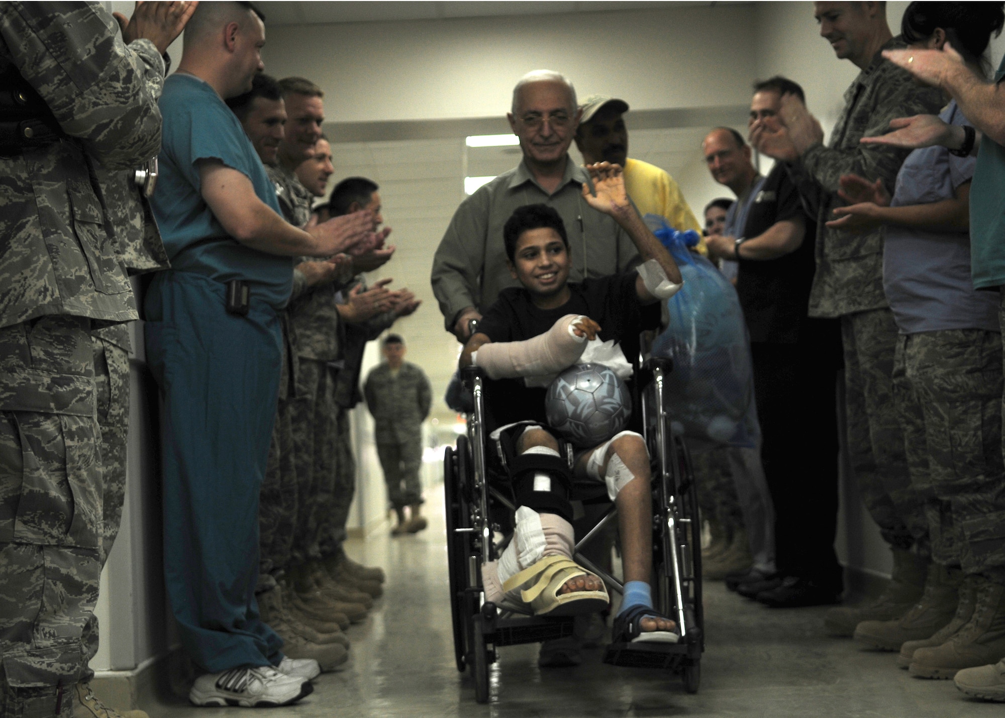 JOINT BASE BALAD, Iraq -- Medical personnel applaud as Ahmad, a 14-year-old Iraqi victim of a mortar explosion, leaves the Air Force Theater Hospital here Sept. 17, 2009, after spending more than a month recovering from his injuries. (U.S. Air Force photo/Staff Sgt. Heather Norris)