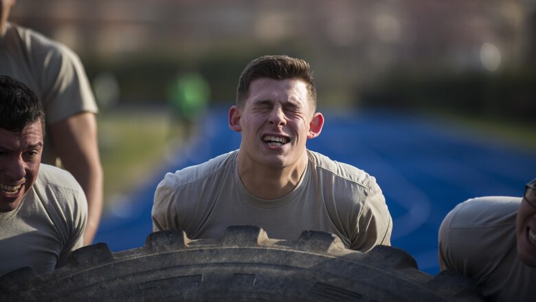 Airman 1st Class Nicholas Castellucci, 724th Air Mobility Squadron member, flips a tire with his teammates during the first Combat Warrior Challenge at Aviano Air Base, March 14, 2017. The four-day competition included obstacles such as a wall climb, tire flip, and kettle bell carry. (U.S. Air Force photo by Senior Airman Cory W. Bush)