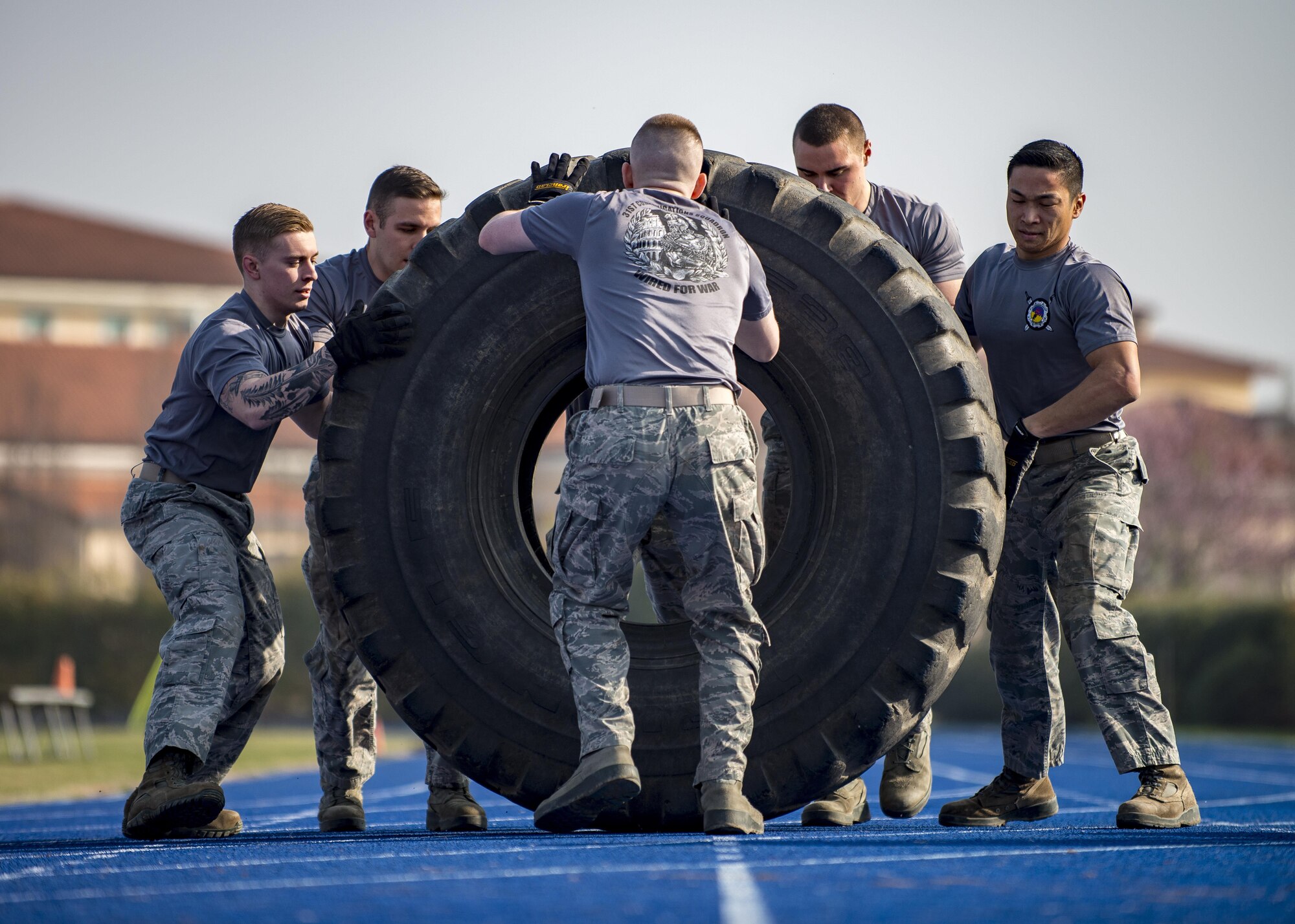 Airmen from the 31st Communications Squadron flip a tire during the final round of the first Combat Warrior Challenge at Aviano Air Base, March 16, 2017. Each team was required to flip a 650 lb. tire 20 times before moving on to the next obstacle. The 31st Communications Squadron team won the competition. (U.S. Air Force photo by Senior Airman Cory W. Bush)