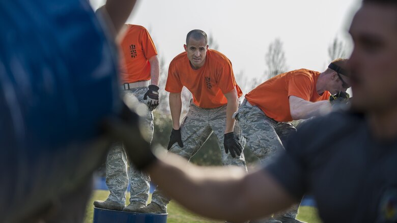 Staff Sgt. Jackie Sanders, 31st Munitions Squadron member, glances at the 31st Communications Squadron team during the barrels portion of the first Combat Warrior Challenge at Aviano Air Base, March 16, 2017. Each team was required to move four barrels 20 yards without participants touching the ground. (U.S. Air Force photo by Senior Airman Cory W. Bush)