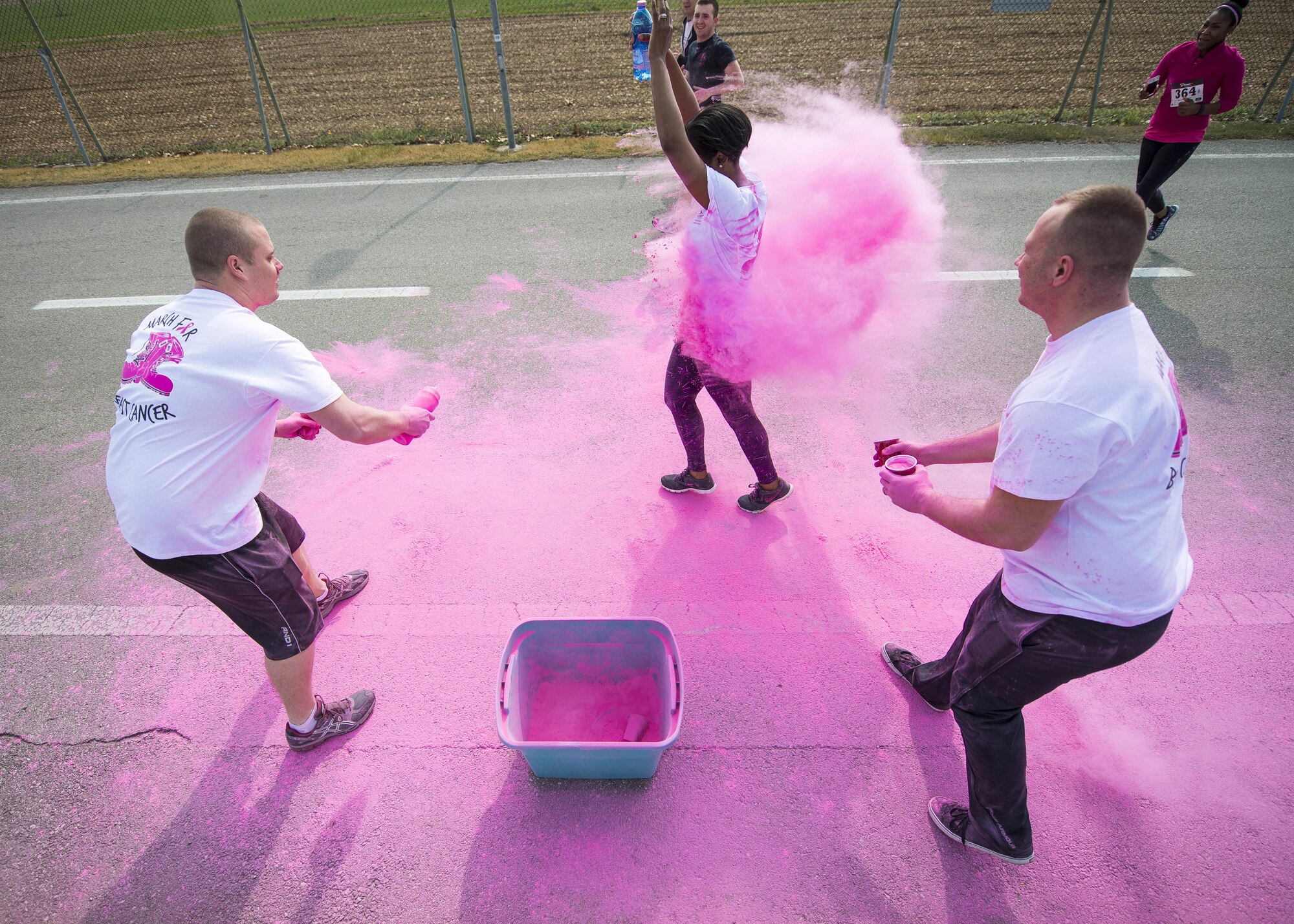 A Team Aviano member runs through pink powder during the 11th Annual Breast Cancer Awareness Walk at Aviano Air Base, Italy, March 18, 2017. The event had its largest turnout and money raised since its inception. (U.S. Air Force photo by Senior Airman Cory W. Bush)