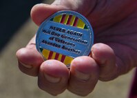 Retired U.S. Air Force Capt. William Robinson, longest surviving enlisted prisoner of war, holds a Vietnam veteran coin after an award ceremony here, March 17, 2017. Robinson was a POW for nearly eight years before being released. Now, Robinson speaks about his experience with community and military members across the country.