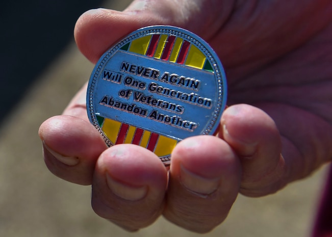 Retired U.S. Air Force Capt. William Robinson, longest surviving enlisted prisoner of war, holds a Vietnam veteran coin after an award ceremony here, March 17, 2017. Robinson was a POW for nearly eight years before being released. Now, Robinson speaks about his experience with community and military members across the country.