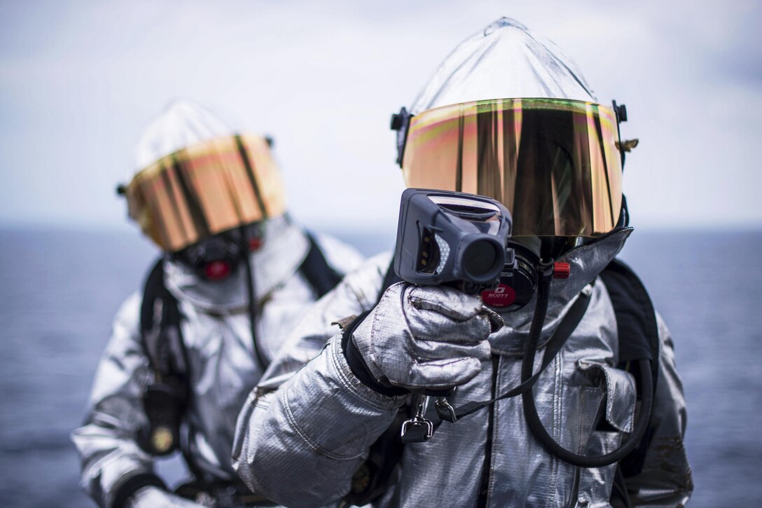 Navy Petty Officer 3rd Class Julessa Heathe, front, and Airman Jovonte Ross search for hot spots during a simulated aircraft fire on the flight deck of the USS Bonhomme Richard in the Philippine Sea, March 18, 2017. The ship is operating in the Indo-Asia-Pacific region to enhance warfighting readiness. Navy photo by Petty Officer 3rd Class Jeanette Mullinax