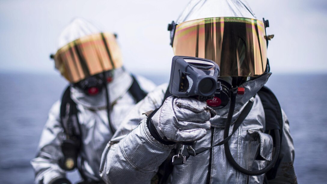 Navy Petty Officer 3rd Class Julessa Heathe, front, and Airman Jovonte Ross search for hot spots during a simulated aircraft fire on the flight deck of the USS Bonhomme Richard in the Philippine Sea, March 18, 2017. The ship is operating in the Indo-Asia-Pacific region to enhance warfighting readiness. Navy photo by Petty Officer 3rd Class Jeanette Mullinax