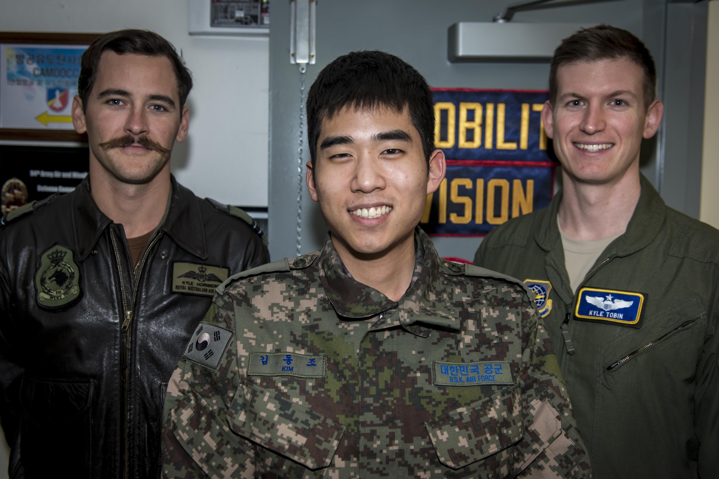 Royal Australian Air Force Flt. Lt. Kyle Hornberg, left, Republic of Korea Air Force 2nd Lt. Dongjo Kim, center, and U.S. Air Force Maj. Kyle Tobin, right, pose for a photo near their workstations in the Korean Air Operations Center at Osan Air Base, Republic of Korea, March 22, 2017. The three work together in the Air Mobility Division ensuring timely airlift support for all Key Resolve 2017 missions. Hornberg is the Air Mobility Division Multinational Coordination Center liaison officer with the Air Mobility Control Center at Royal Australian Air Force Base Richmond, Australia, Kim is an interpreting officer with the Air Component Command’s join plans and coordination division at Osan AB, and Tobin is with the 621st Air Mobility Squadron at Joint Base McGuire-Dix-Lakehurst, New Jersey. (U.S. Air Force photo by Staff Sgt. Benjamin W. Stratton)