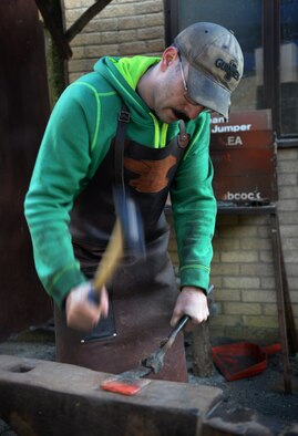 U.S. Air Force Tech. Sgt. Steven Pyott, 100th Security Forces Squadron standards and evaluations sections evaluator and blacksmith, strikes the steel with a hammer Feb. 11, 2017, in Suffolk, England. He continues this process until the steel takes on the desired shape. (U.S. Air Force photo by Airman 1st Class Tenley Long)