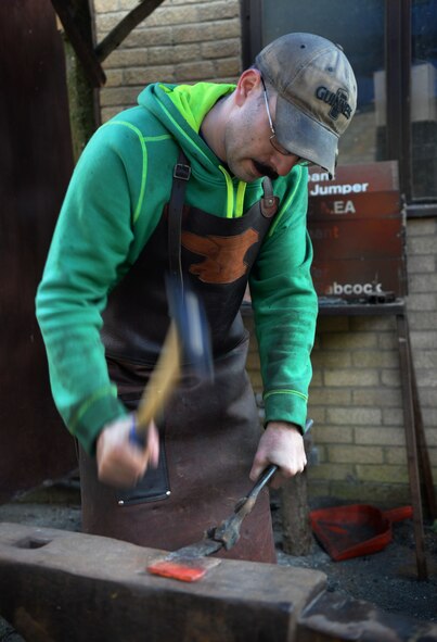 U.S. Air Force Tech. Sgt. Steven Pyott, 100th Security Forces Squadron standards and evaluations sections evaluator and blacksmith, strikes the steel with a hammer Feb. 11, 2017, in Suffolk, England. He continues this process until the steel takes on the desired shape. (U.S. Air Force photo by Airman 1st Class Tenley Long)