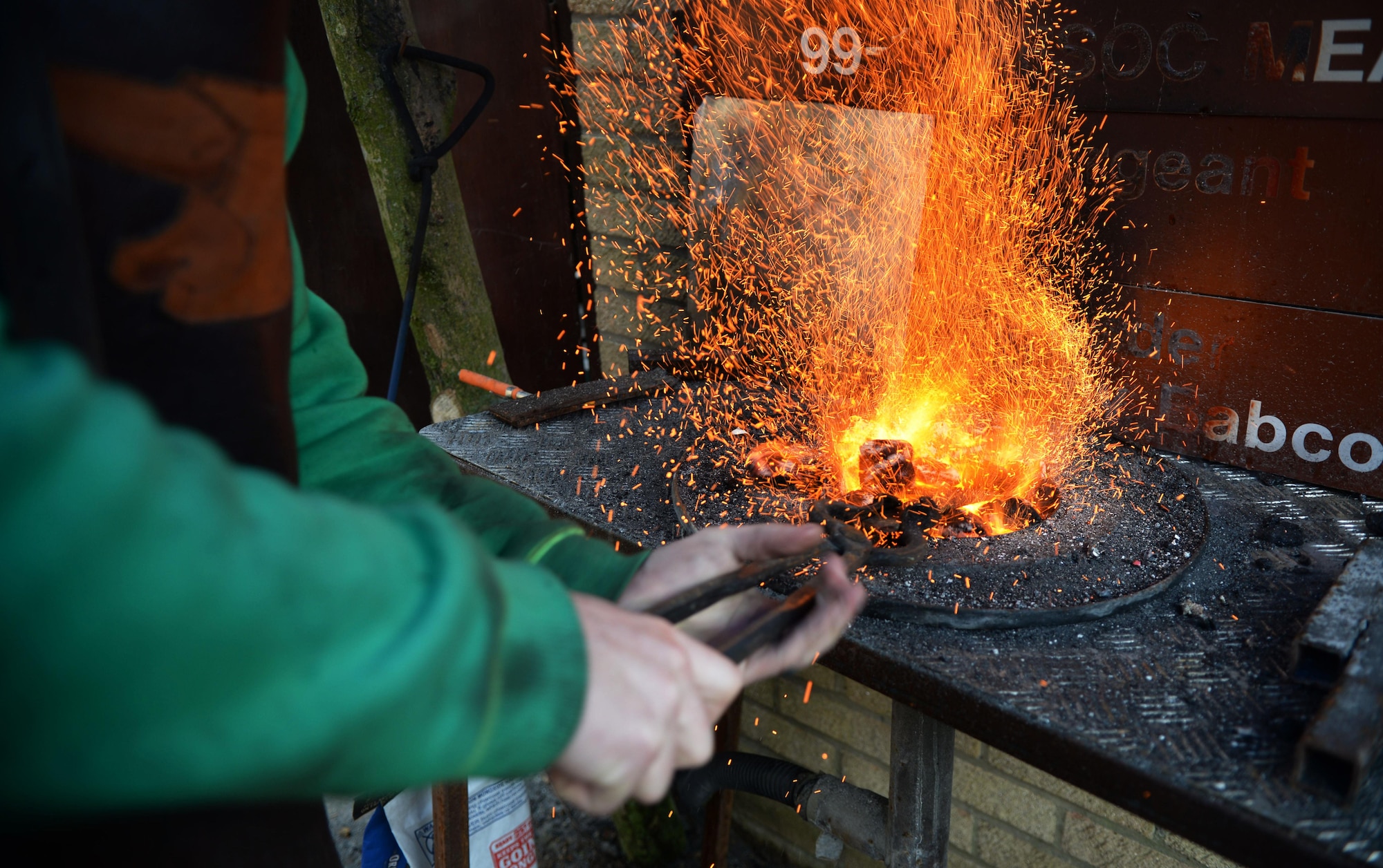 U.S. Air Force Tech. Sgt. Steven Pyott, 100th Security Forces Squadron standards and evaluations sections evaluator and blacksmith, inserts the steel into the fire Feb. 11, 2017, in Suffolk, England. The steel heats rapidly because the coals act like an oven, trapping the heat. (U.S. Air Force photo by Airman 1st Class Tenley Long)