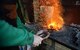 U.S. Air Force Tech. Sgt. Steven Pyott, 100th Security Forces Squadron standards and evaluations sections evaluator and blacksmith, inserts the steel into the fire Feb. 11, 2017, in Suffolk, England. The steel heats rapidly because the coals act like an oven, trapping the heat. (U.S. Air Force photo by Airman 1st Class Tenley Long)