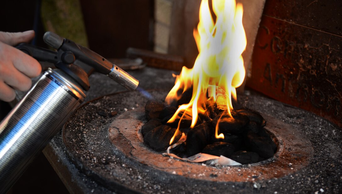 U.S. Air Force Tech. Sgt. Steven Pyott, 100th Security Forces Squadron standards and evaluations sections evaluator and blacksmith, creates a fire Feb. 11, 2017, in Suffolk, England. During blacksmithing, Pyott uses charcoal to light the fire, then uses a blower to introduce air into the coal. (U.S. Air Force photo by Airman 1st Class Tenley Long)
