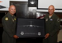 Col. Jimmy Canlas, left, 437th Airlift Wing commander, presents Brig. Gen. Brian Robinson, right, Headquarters Air Mobility Command director of operations, with a picture of a C-17 Globemaster during an Operations Call for pilots assigned to the 437th AW at Joint Base Charleston, South Carolina, March 21. Robinson toured various facilities and met with key leadership during his visit.