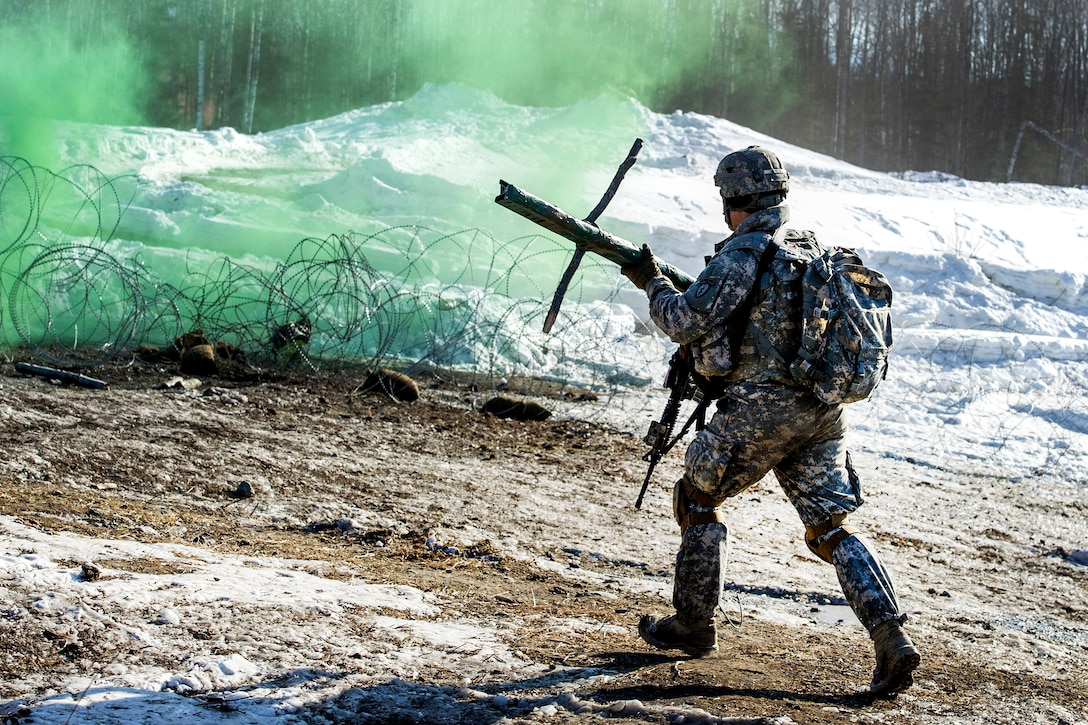 A soldier rushes to place an explosive charge on a wire obstacle during live-fire training at the Infantry Platoon Battle Course, Joint Base Elmendorf-Richardson, Alaska, March 17, 2017. Air Force photo by Alejandro Pena