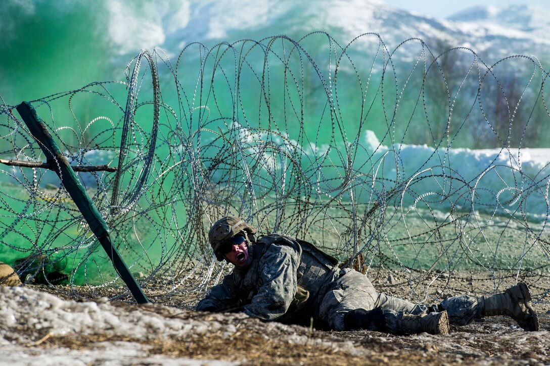 Army Sgt. Zachary Hudson yells instructions while setting up an explosive charge on a wire obstacle during live-fire training at the Infantry Platoon Battle Course, Joint Base Elmendorf-Richardson, Alaska, March 17, 2017. Hudson is assigned to the 25th Infantry Division’s Company A, 6th Brigade Engineer Battalion, 4th Infantry Brigade Combat Team (Airborne). Air Force photo by Alejandro Pena