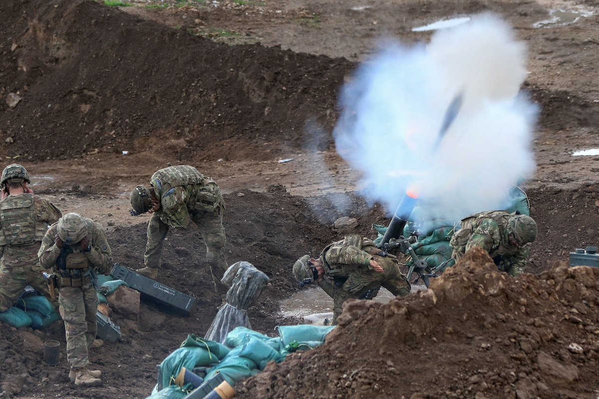 Soldiers fire mortar rounds from a trench during a fire mission in Iraq.