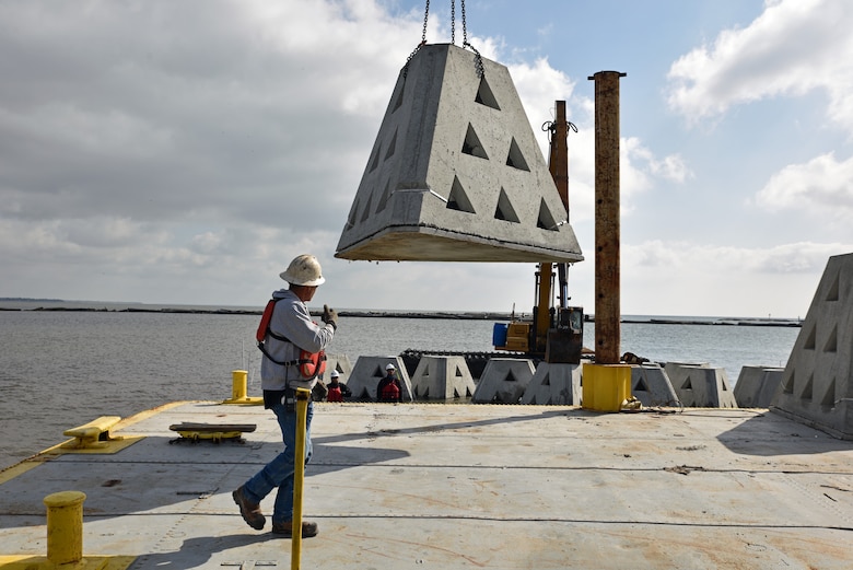 Construction workers unload a wave attenuation device (WAD) into the water near Bayou Caddy with a barge-mounted crane. The U.S. Army Corps of Engineers, Mobile District, used the WADs as part of a living shoreline to reduce wave energy.