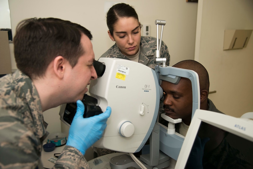 U.S. Air Force Tech. Sgt. Christopher Hutchinson, left, a 35th Aerospace Medicine Squadron optometry technician, with the assistance from Senior Airman Cassandra Diyer, center, 35th AMDS medical technician, takes a photo of the back of a patient’s eye with a fundus camera at Misawa Air Base, Japan, March 9, 2017. Fundus photography photographs the interior surface of the eye, including the retina, retinal vasculature, optic disc, macula and posterior pole. Eye care is a key role in providing combat-ready Airmen, who are the foundation of Pacific Air Forces stability and security. (U.S. Air Force photo by Staff Sgt. Melanie A. Hutto)