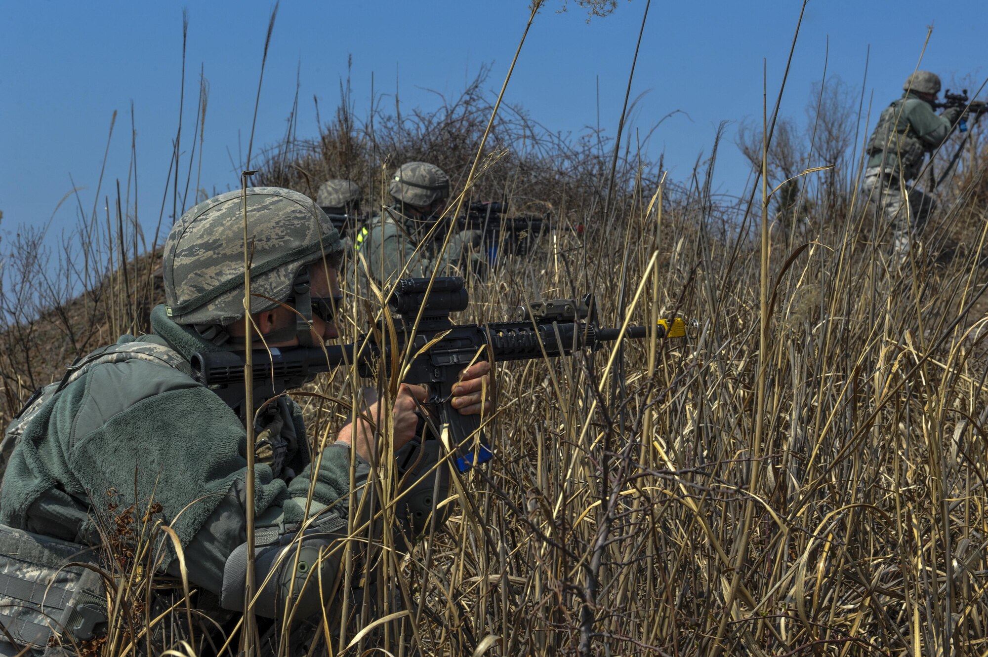 U.S. Air Force 8th Security Forces Squadron members advance through high bush while scanning for opposing forces during a field training exercise at Kunsan Air Base, Republic of Korea, March 17, 2017. Opposing forces attack the security forces members to test their teamwork and communication skills under stressful situations. (U.S. Air Force photo by Senior Airman Colville McFee/Released)