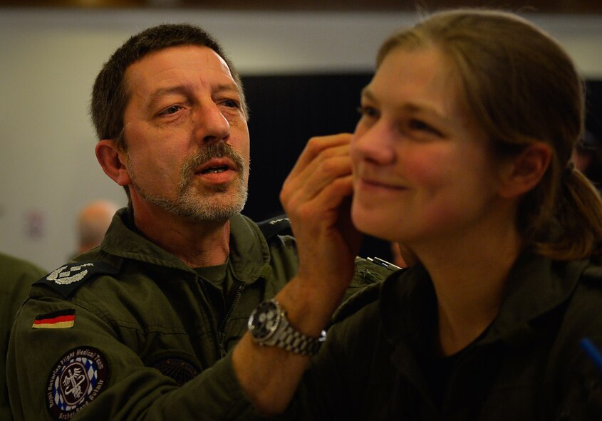 Lt. Col. Michael Kiefer, a German Air Force flight surgeon, gives battlefield acupuncture to Maj. Tanja Drews, also a German Air Force flight surgeon, during an aerospace medicine conference on Ramstein Air Base, Germany, March 21, 2017. Although battlefield acupuncture originated as a method to give quick pain relief to troops in battle, the practice made its way into non-combat environments. (U.S. Air Force photo by Airman 1st Class Joshua Magbanua)