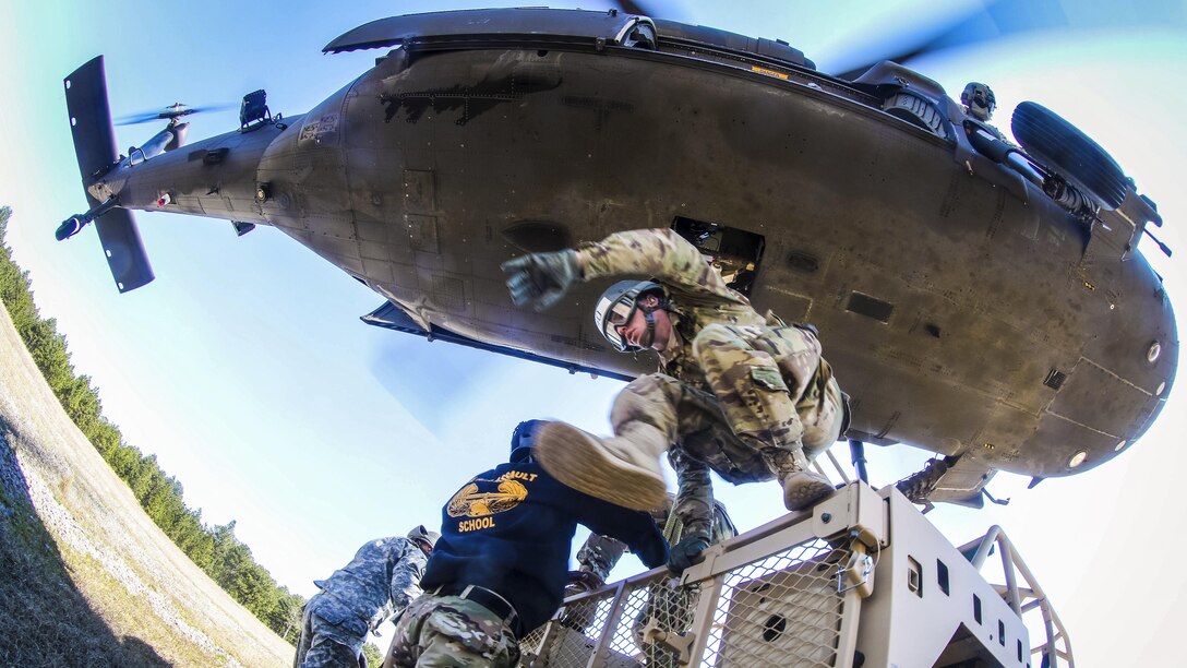 A soldier from the DeGlopper Air Assault School jumps off a tactical vehicle after connecting a slingload onto a UH-60 Black Hawk helicopter on Fort Bragg, N.C., March 23, 2017. The helicopter is assigned to the assigned to the 2nd Assault Helicopter Battalion, 82nd Combat Aviation Brigade. Army photo by Capt. Adan Cazarez