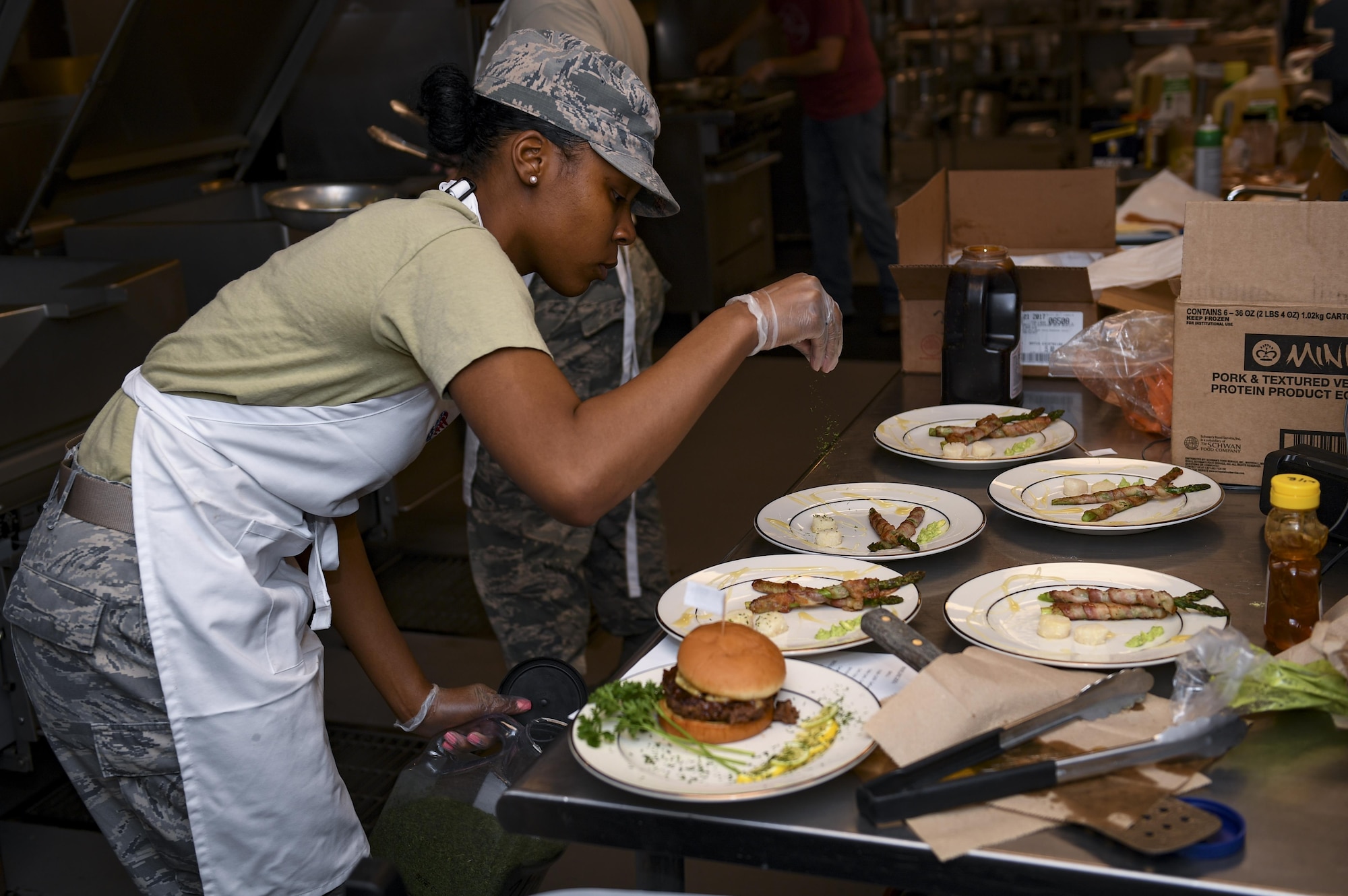 Senior Airman Shakilah Bates, 23d Force Support Squadron food service specialist, adds the finishing touches to her dishes moments before the conclusion of the first Iron Chef Competition held at the Georgia Pines Dinning Facility, March 23, 2017, at Moody Air Force Base, Ga. Four teams were given an hour to prepare their meals for the judges. The 23d Force Support Squadron plans to hold at least one Iron Chef Competition per year. (U.S. Air Force photo by Airman 1st Class Daniel Snider)