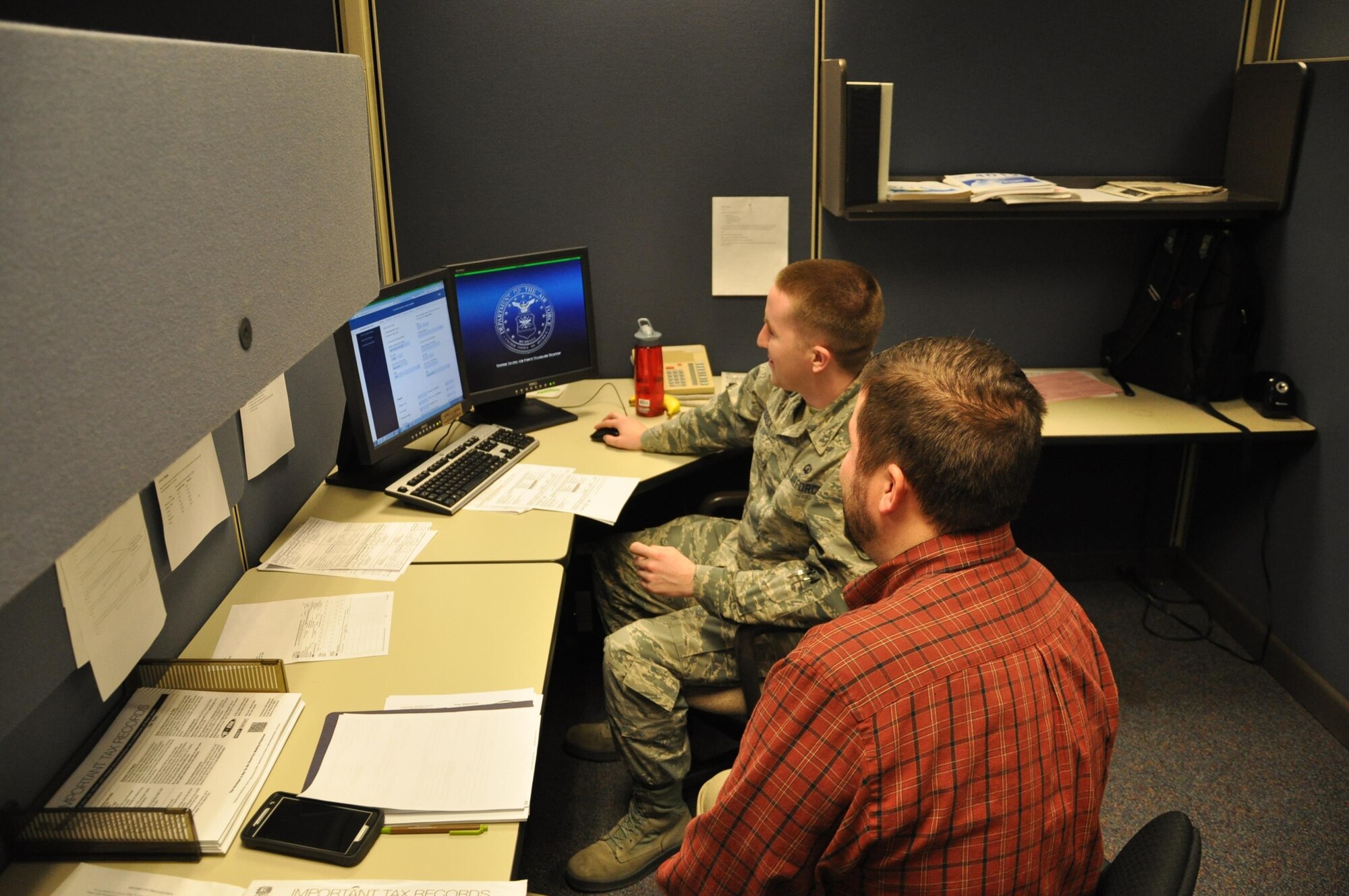 Senior Airman Adam Hudock, a representative at the base tax preparation center, assists Ben Walters with his tax return. (U.S. Air Force photo/W. Eugene Barnett Jr.)