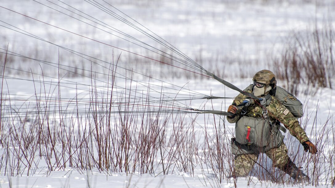 Air Force Master Sgt. Logan English recovers his parachute after landing on Malemute drop zone during helicopter jump training at Joint Base Elmendorf-Richardson, Alaska, March 22, 2017. Air Force photo by Alejandro Pena