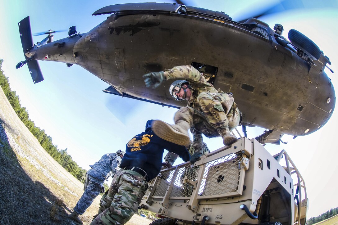 A soldier from the DeGlopper Air Assault School jumps off a tactical vehicle after connecting a slingload onto a UH-60 Black Hawk helicopter on Fort Bragg, N.C., March 23, 2017. The helicopter is assigned to the assigned to 2nd Assault Helicopter Battalion, 82nd Combat Aviation Brigade. Army photo by Capt. Adan Cazarez