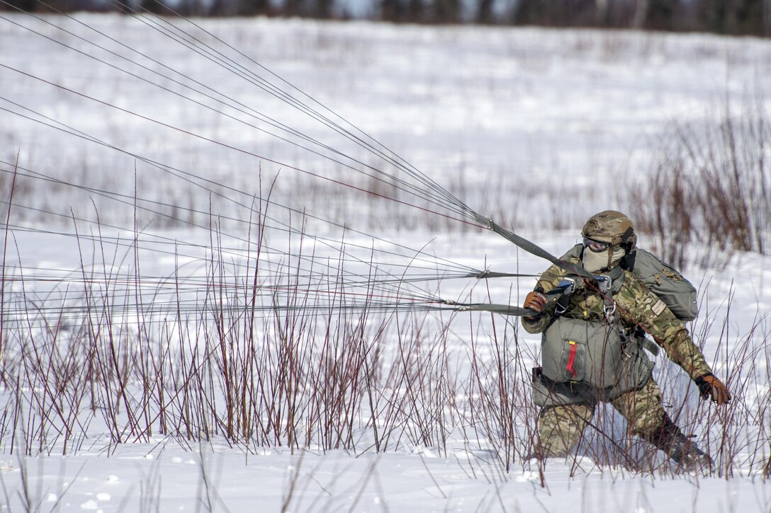 Air Force Master Sgt. Logan English recovers his parachute after landing on Malemute drop zone during helicopter jump training at Joint Base Elmendorf-Richardson, Alaska, March 22, 2017. Air Force photo by Alejandro Pena