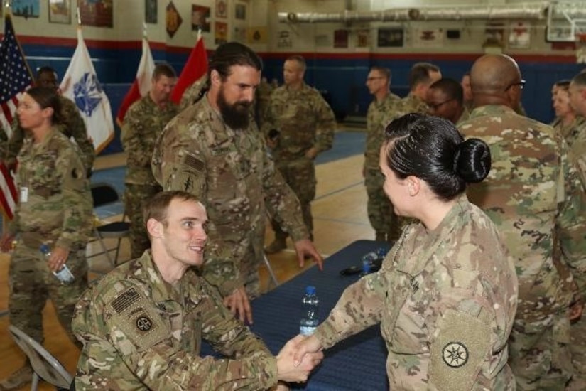 Retired Army Sgt. Willard Hoyum, wheeled vehicle mechanic, formerly with A company, 307th Brigade Support Battalion, 82nd Airborne Division, shakes the hand of a deployed Soldier, March 14, 2017, Camp Arifjan, Kuwait. The meet and greet concluded the first town hall meeting Soldiers of Operation Proper Exit will give prior to returning to the location where they received their combat injuries.