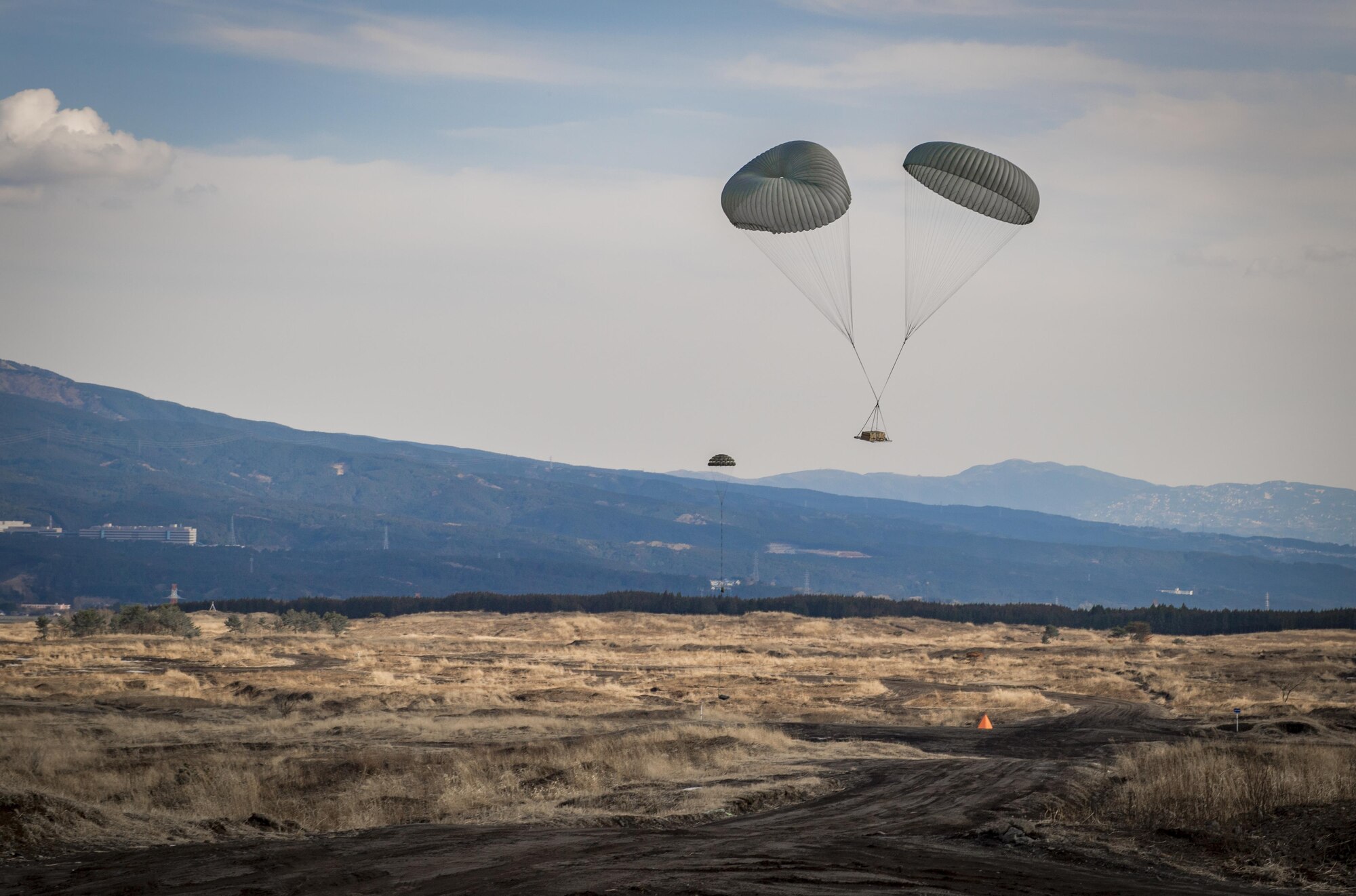 A heavy cargo pallet floats to the ground after being dropped from a C-130J Super Hercules during a cargo drop training exercise March 22, 2017, at Camp Fuji, Japan. The exercise included a small cargo load to simulate supplying food, water or ammunition, and a heavy cargo load to simulate vehicle delivery to combat or contingency operations. (U.S. Air Force photo by Airman 1st Class Donald Hudson)