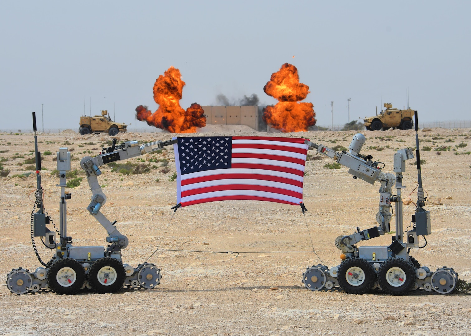 Two “fireball” charges go off behind a U.S. flag being held by F6A bomb disposal robots at Al Udeid Air Base, Qatar, March 17, 2017. The 379th Expeditionary Civil Engineer Squadron Explosive Ordnance Flight set off several rounds of explosives to mark the grand opening of their new EOD range at Al Udeid. (U.S. Air Force photo by Senior Airman Miles Wilson)