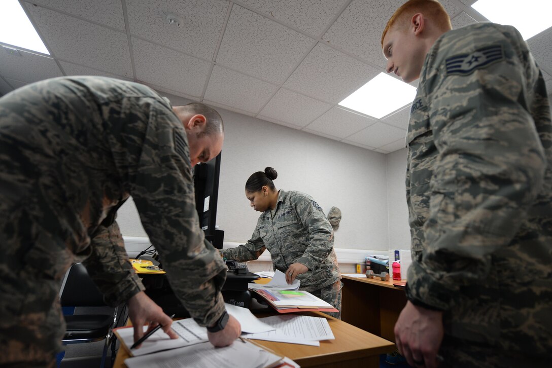 U.S. Air Force Air National Guard Tech. Sgt. Kyle Klineman, left, 194th Force Support Squadron NCO in charge of installation personnel readiness, and U.S. Air Force Tech. Sgt. Danielle Mercer, 100th FSS Installation Personnel Readiness section chief, review deployment folders with Staff Sgt. Aaron Web, right, 100th FSS unit deployment manager, March 23, 2017, on RAF Mildenhall, England. Deployers must out-process the base through IPR to ensure they have met all the requirements need for their deployed location. (U.S. Air Force photo by Staff Sgt. Micaiah Anthony)