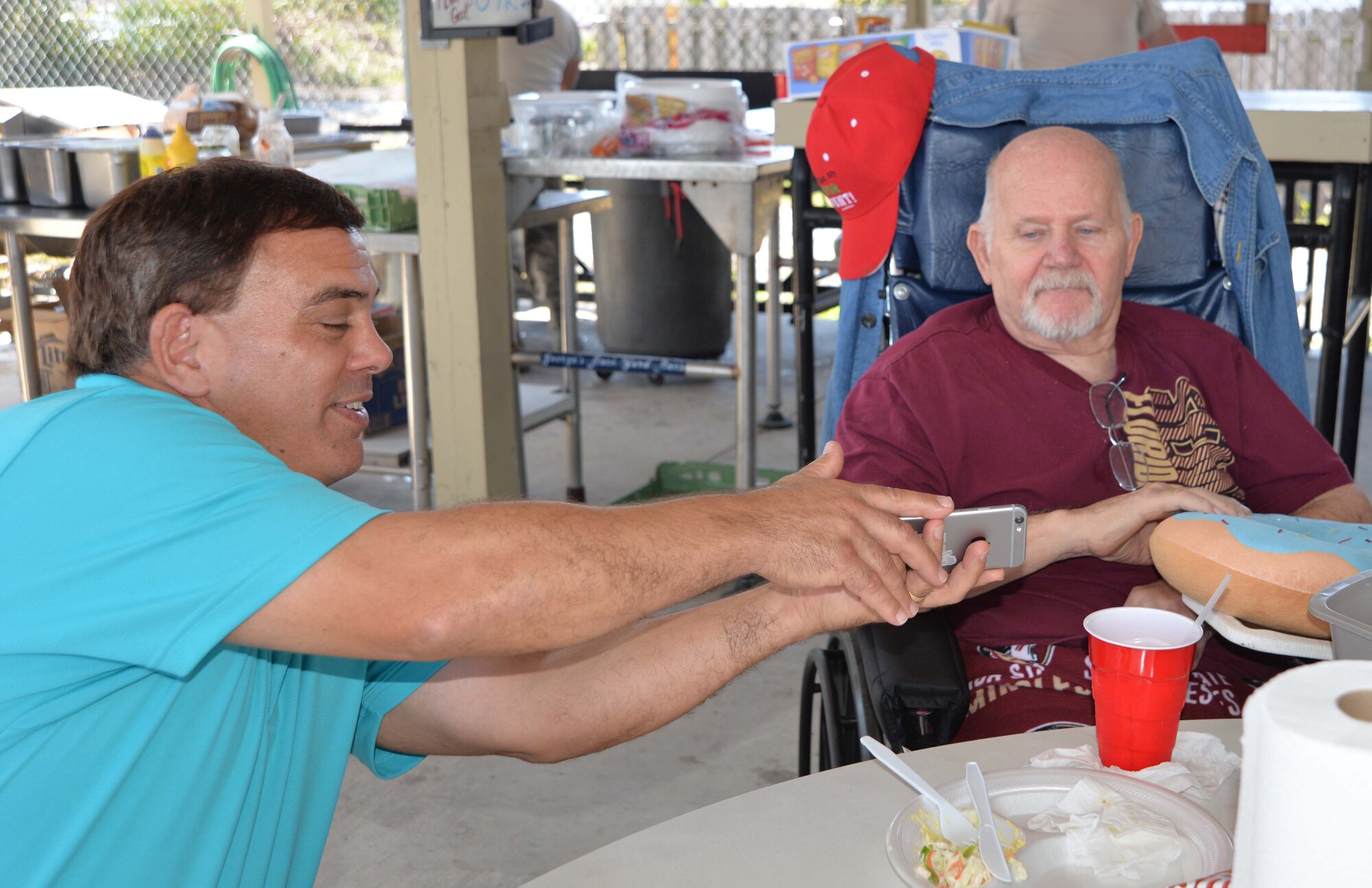 Dan Phillips, Continental U.S. NORAD Region-1st Air Force (Air Forces Northern) Communication & Information Directorate, shows a photo from his phone to Johnny Mack Jones, a resident of the Clifford Chester Sims State Veterans Nursing Home, during a luncheon at American Legion Post 392 in Panama City. Event organizer David Shaw, a Legion member from CONR-1st AF (AFNORTH), said the luncheon was an opportunity to spend time with the veterans and recognize them for their selfless service and sacrifice. (Photo by Mary McHale)