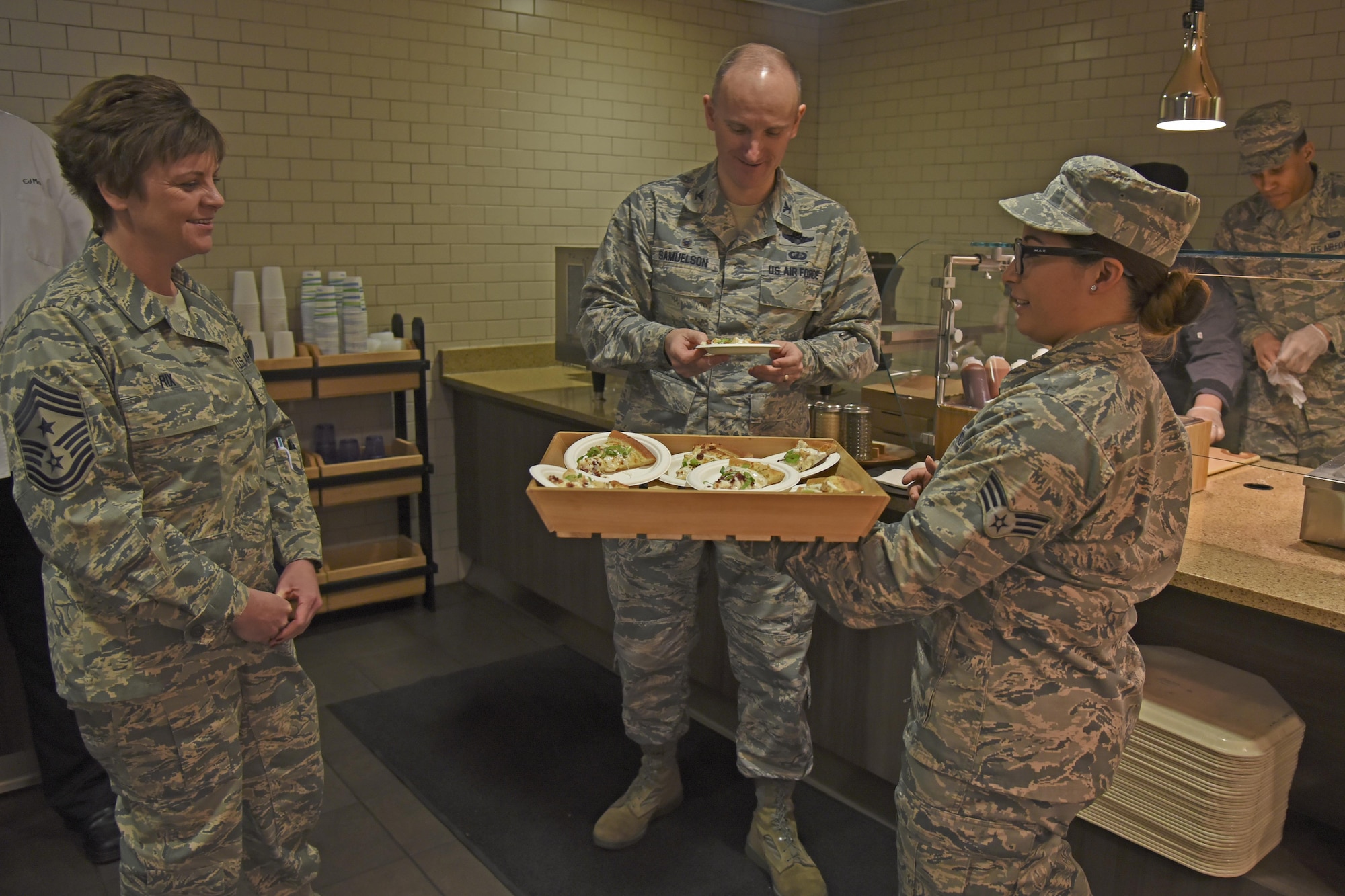 Col. Ryan Samuelson, 92nd Air Refueling Wing commander, and Chief Master Sgt. Shannon Rix, 92nd ARW command chief, taste test new Warrior Mission Essential Feeding Facility options during a ribbon-cutting ceremony Mar. 27, 2017, at Fairchild Air Force Base, Washington. Senior Airman Samantha Acevedo, 92nd Force Support Squadron services journeyman, presented the healthier, made-to-order CIAO Pizzeria to base leadership. (U.S. Air Force photo/Senior Airman Mackenzie Richardson)