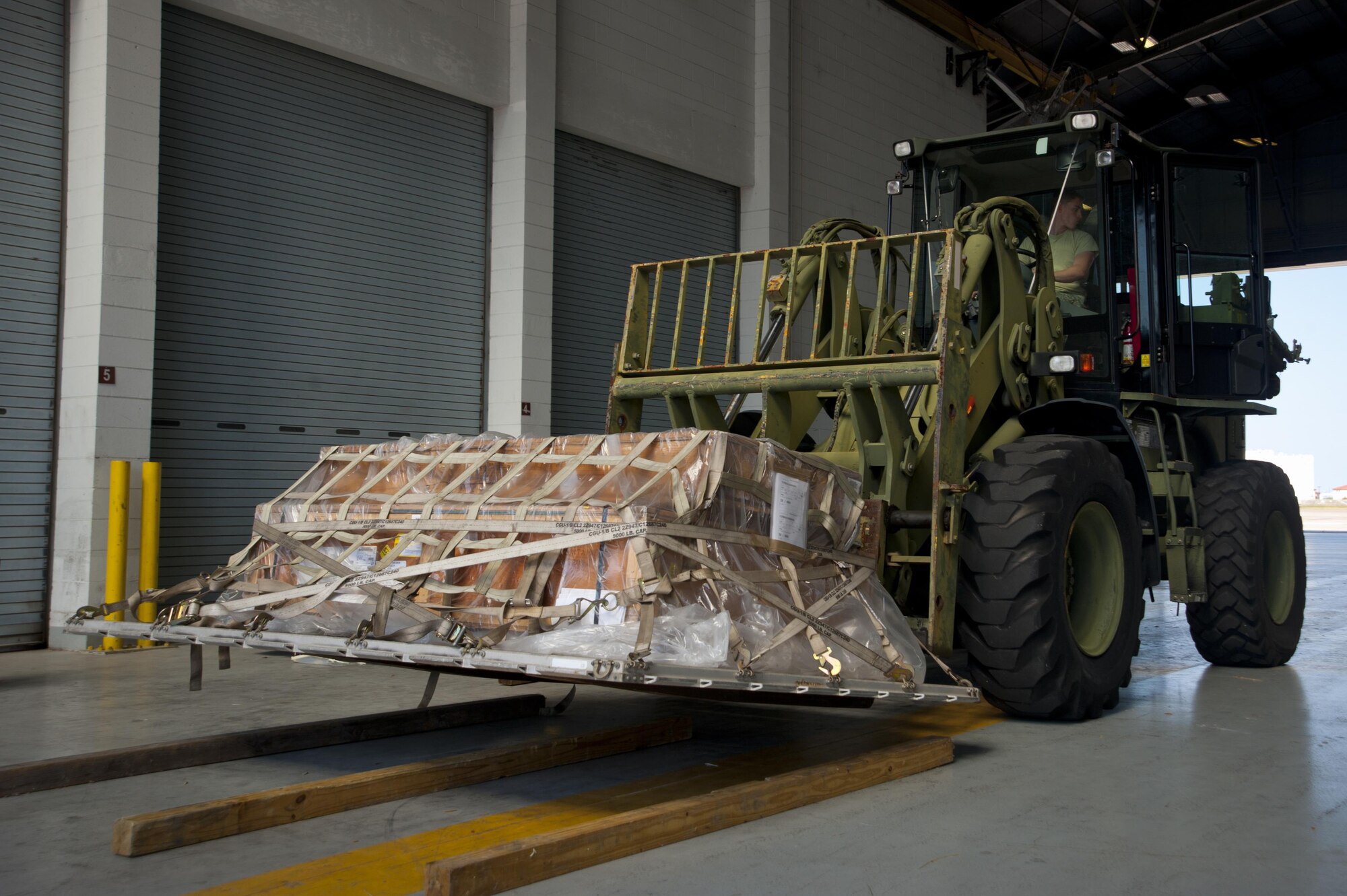 Senior Airman Landon Adams, a vehicle operator with the 6th Logistics Readiness Squadron, lifts a pallet in hangar two in order to transfer it to the cargo deployment function yard during an exercise at MacDill Air Force Base, Fla., March 21, 2017. Once the pallet has been inspected, it may be placed on the aircraft for deployment. (U.S. Air Force photo by Airman 1st Class Mariette Adams)