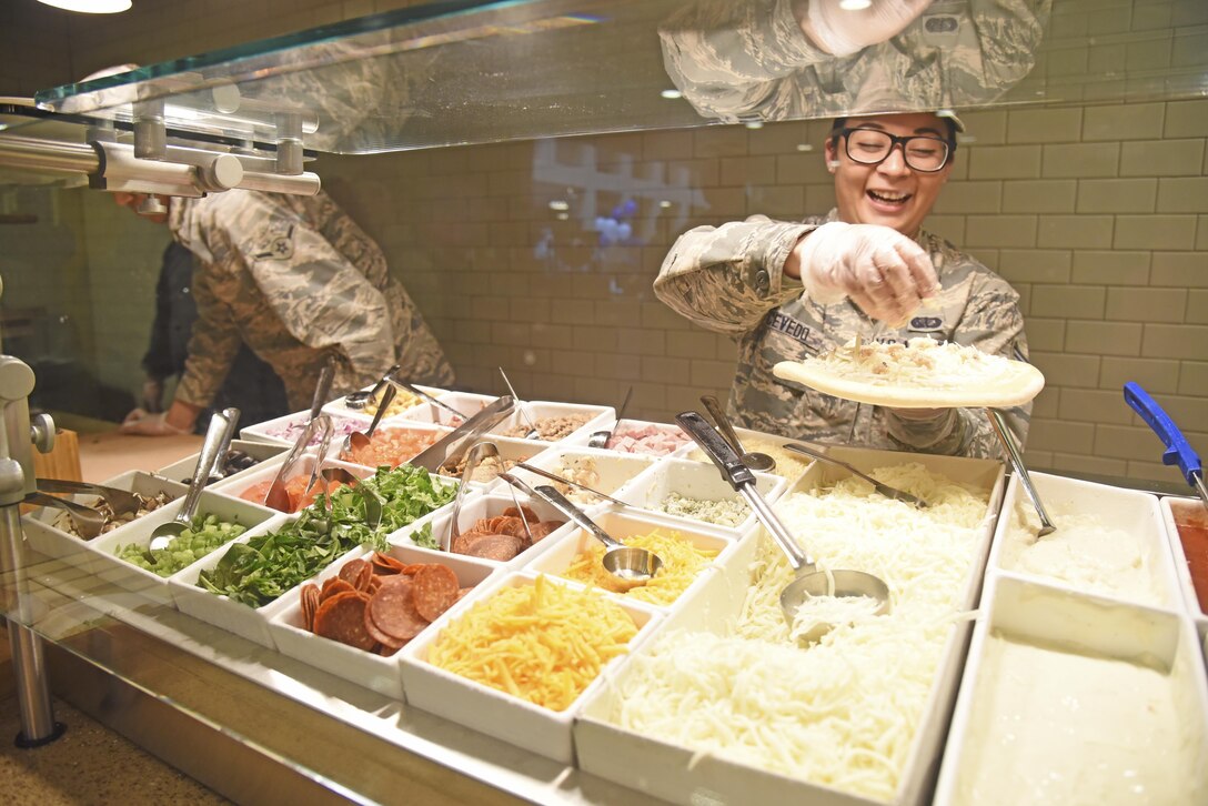 Senior Airman Samantha Acevedo, 92nd Force Support Squadron services journeyman, creates a custom pizza at CIAO Pizzeria Mar. 27, 2017, at Fairchild Air Force Base. Fairchild's Warrior and Ross Mission Essential Feeding Facilities are the third base feeding facilities in the Air Force to expand on the standard Food Transformation Initiative. (U.S. Air Force photo/Senior Airman Mackenzie Richardson)