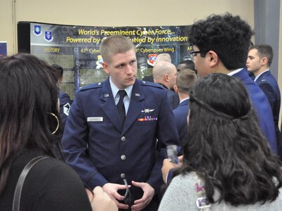 First Lt. Eric Kenney, 390th Cyberspace Operations Center, speaks with high schoolers about the Air Force cyber mission during an information fair at the annual Mayor's Cyber Cup banquet March 25 in San Antonio, Texas. The students all competed in the Air Force Association CyberPatriot challenge, a nationwide program in which teams of students learn to harden network security and then compete to defend systems against intrusions.  