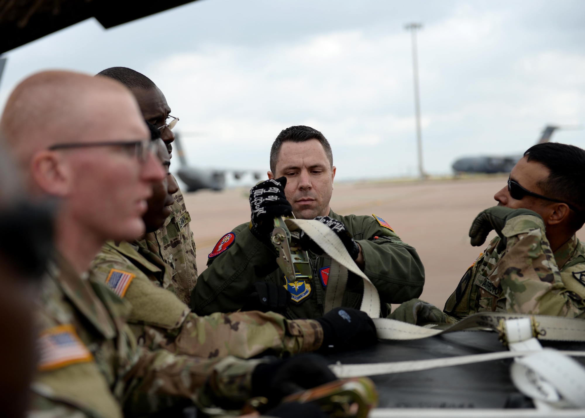 U.S. Air Force Staff Sgt. C.J. Crew, 58th Airlift Squadron instructor loadmaster, demonstrates how to properly secure a cargo pallet U.S. Army Soldiers assigned to the 578th Forward Support Company at Fort Sill, Oklahoma, March 23, 2017, at Altus Air Force Base, Oklahoma. The soldiers came to Altus AFB to learn how to secure cargo pallets and vehicles to a U.S. Air Force C-17 Globemaster III cargo aircrafts. (U.S. Air Force photo by Airman 1st Class Jackson N. Haddon/Released).