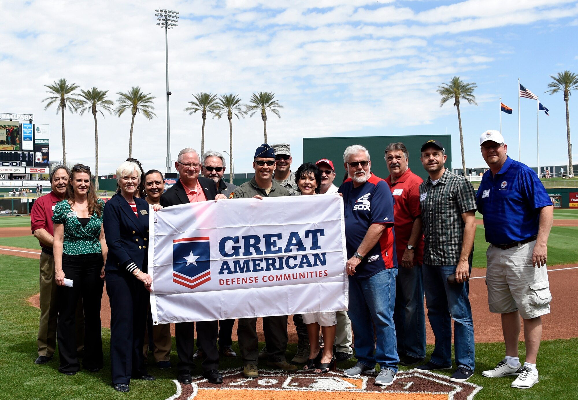 Brig Gen. Brook Leonard, 56th Fighter Wing commander, and Chief Master Sergeant Randall Kwiatkowski, 56th Fighter Wing command chief, along with Maricopa County officials, hold the Great American Defense Communities banner during the Cleveland Indians and Chicago White Sox Spring Training game March 25, 2017, at the Goodyear Ballpark in Goodyear, Ariz. The Great American Defense Community award is a recognition of the unique contribution cities, counties, and regions make to improve quality of life for service members, veterans and their families. (U.S. Air Force photo by Airman 1st Class Alexander Cook)