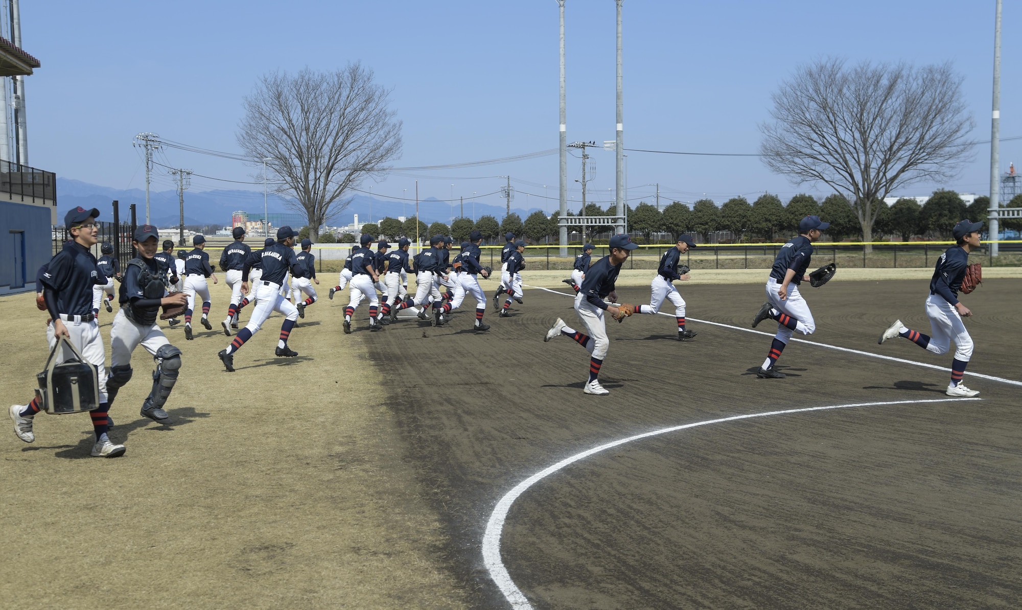 Members of the Chofu Little Seniors baseball team run out onto the field to warm-up prior to the Inaugural Japan-US Friendship Youth Baseball Game at Yokota Air Base, Japan, March 25, 2017. Chofu’s team won 30-1 during the six inning game. (U.S. Air Force photo by Staff Sgt. David Owsianka)