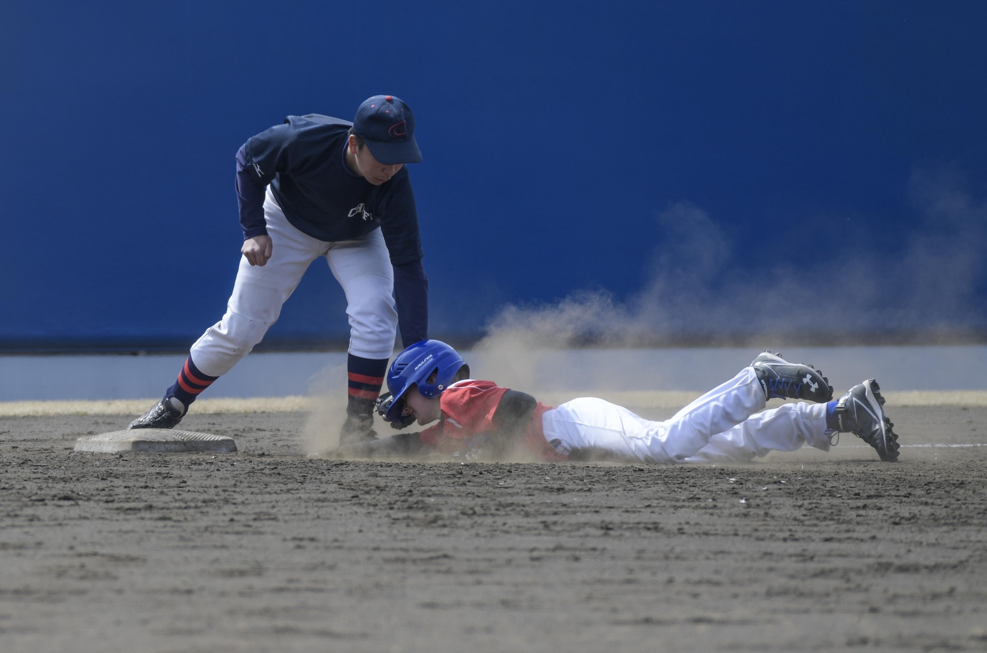 A player from the Yokota Samurai baseball team is tagged out while sliding into third base during the Inaugural Japan-US Friendship Youth Baseball Game at Yokota Air Base, Japan, March 25, 2017. The Yokota Samurai Baseball team consists of 23 players from Yokota’s middle and high schools. (U.S. Air Force photo by Staff Sgt. David Owsianka)