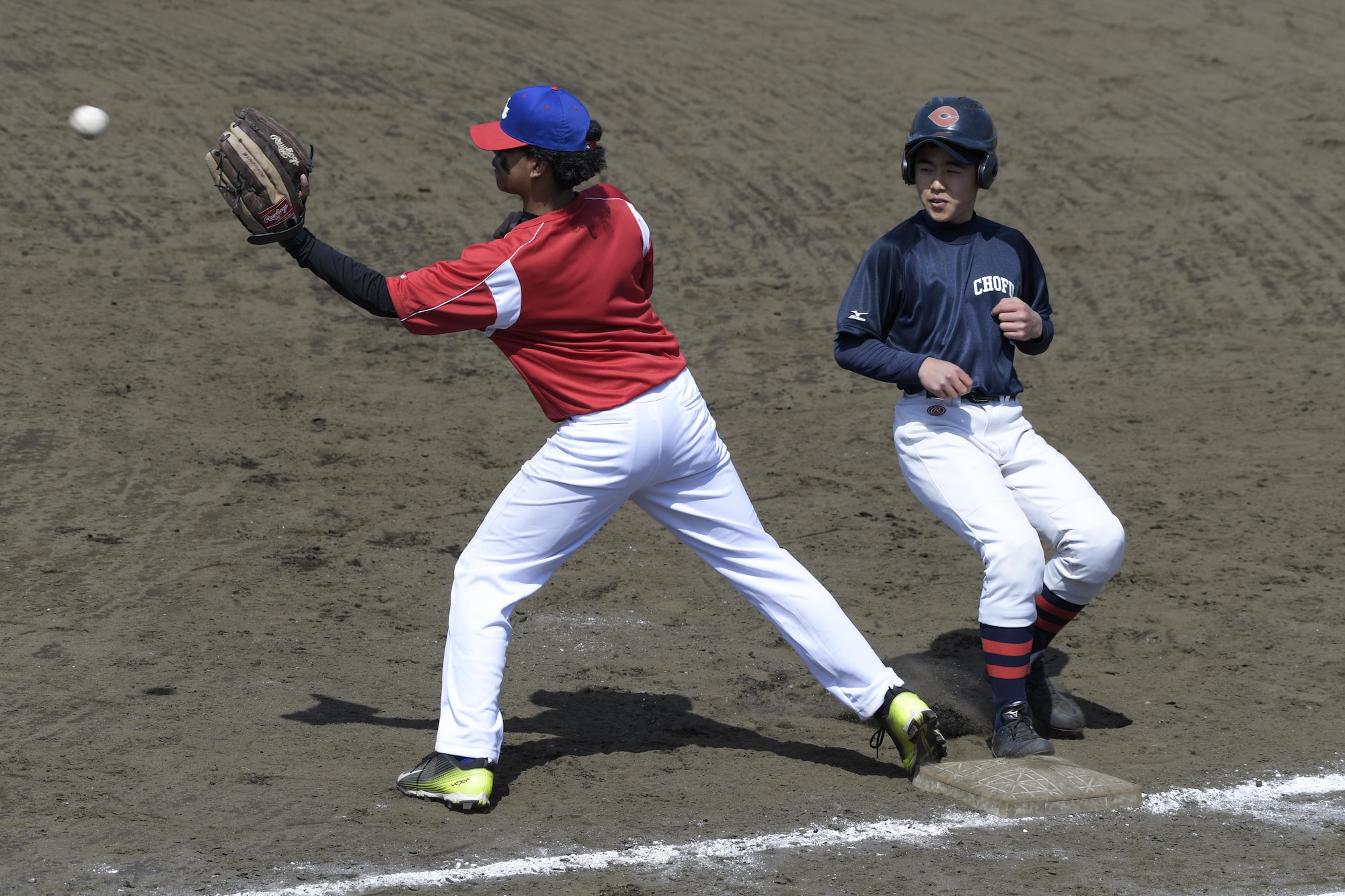 A player from the Chofu Little Seniors team touches first base before the Yokota Samurai team player catches the ball during the Inaugural Japan-US Friendship Youth Baseball Game at Yokota Air Base, Japan, March 25, 2017. Chofu won 30-1 during the six inning game. (U.S. Air Force photo by Staff Sgt. David Owsianka)