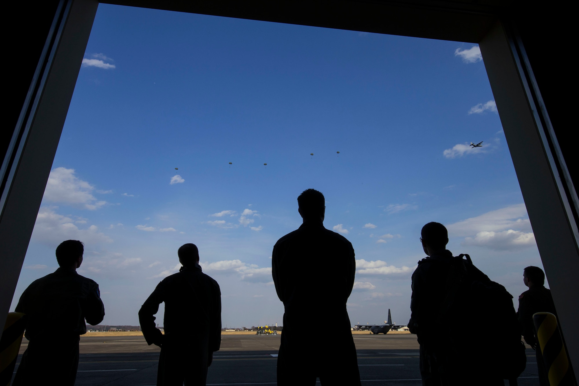 U.S. Air Force aircrews with the 36th Airlift Squadron watch U.S. Marine jumpers descend from an Air Force C-130H Hercules at Yokota Air Base, Japan, March 23, 2017, during jump week. The training not only allowed the Marines to practice jumping, but it also allowed the Yokota aircrews to practice flight tactics and timed-package drops. (U.S. Air Force photo by Yasuo Osakabe)