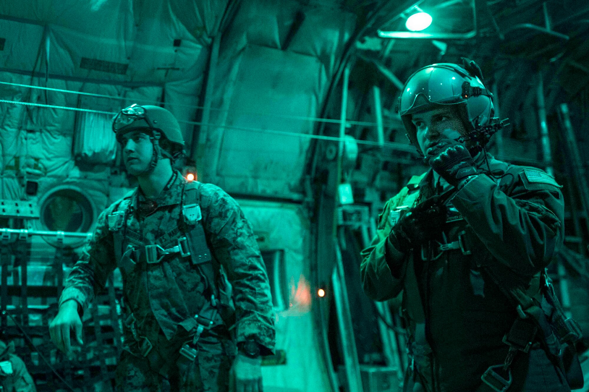 U.S. Air Force Airman 1st Class Stephen Clark, right, C-130H loadmaster, communicates with crew members before U.S. Marines perform static line jump over the drop zone in Yokota Air Base, Japan, during jump week, March 23, 2017. The training not only allowed the Marines to practice jumping, but it also allowed the Yokota aircrews to practice flight tactics and timed-package. (U.S. Air Force photo by Yasuo Osakabe)