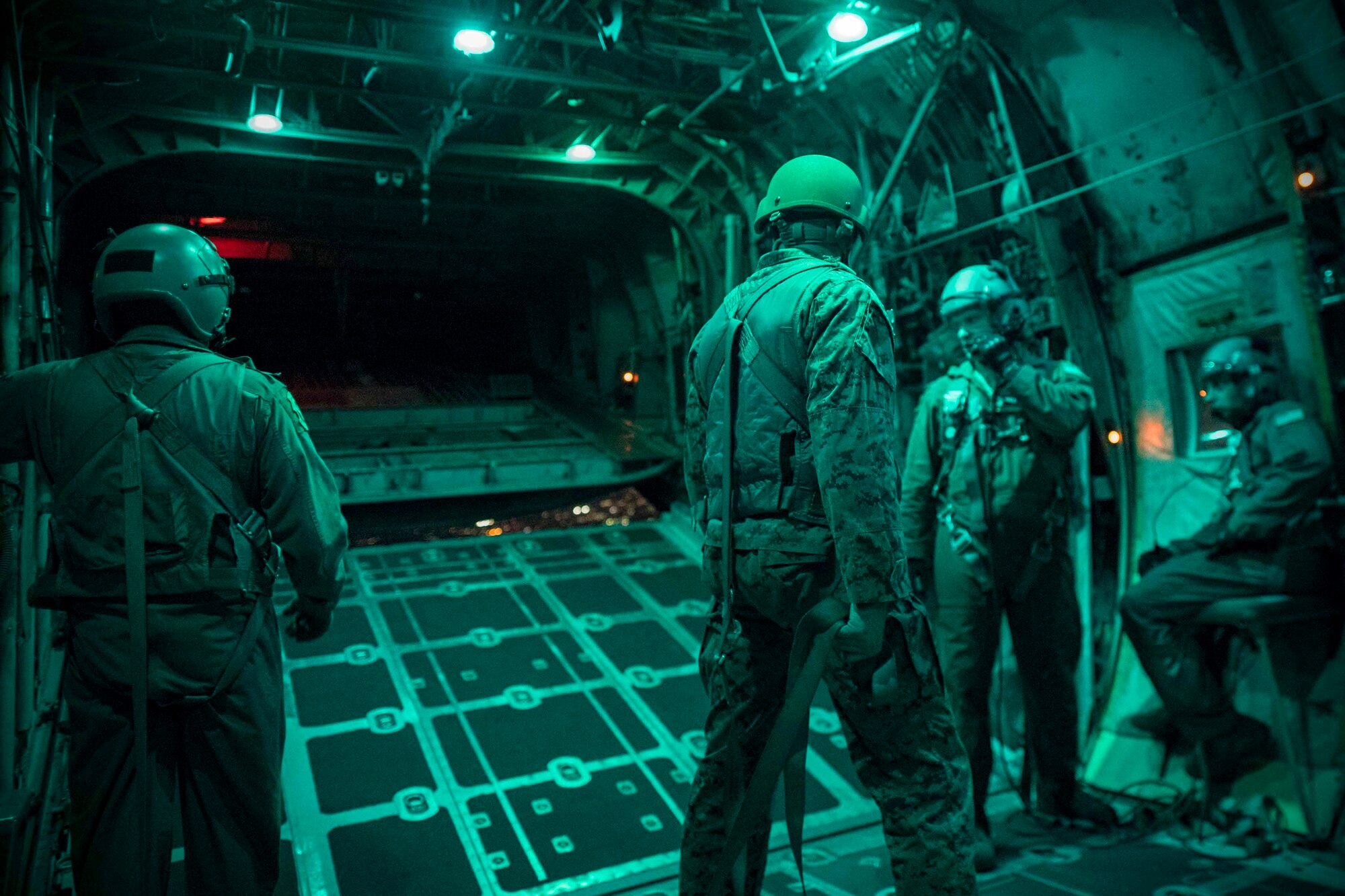 U.S. Marine jumpmaster, center, and Air Force loadmasters with the 36th Airlift Squadron, observe the ramp opening during jump week over Yokota Air Base, Japan, March 23, 2017. The training not only allowed the Marines to practice jumping, but it also allowed the Yokota aircrews to practice flight tactics and timed-package drops day and night. (U.S. Air Force photo by Yasuo Osakabe)