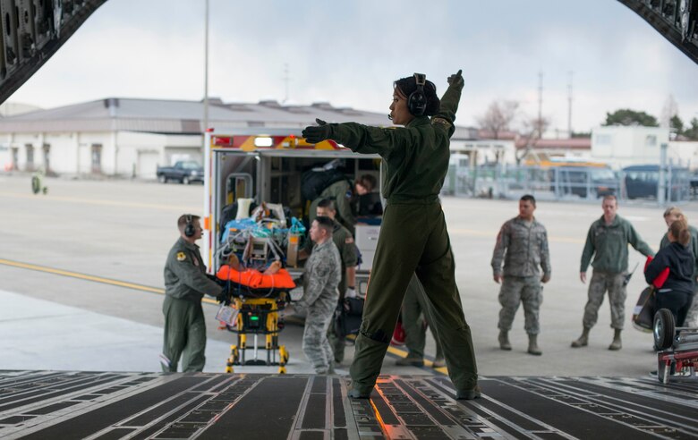U.S. Air Force Capt. Lynn Nguyen, a 18th Aeromedical Evacuation Squadron flight nurse, guides medical personnel onto a C-17 Globemaster III during an aeromedical evacuation at Misawa Air Force Base, Japan, March 22, 2017. Medical professionals from across the world came together to transport a critical patient to Brooke Army Medical Center at Fort Sam Houston, Texas. (U.S. Air Force photo by Senior Airman Brittany A. Chase)
